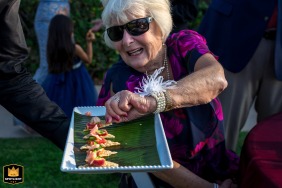   At a wedding reception in Camarillo, CA, an elder guest reaches eagerly for the appetizers, illustrating the relaxed and happy atmosphere among the friends and family gathered.